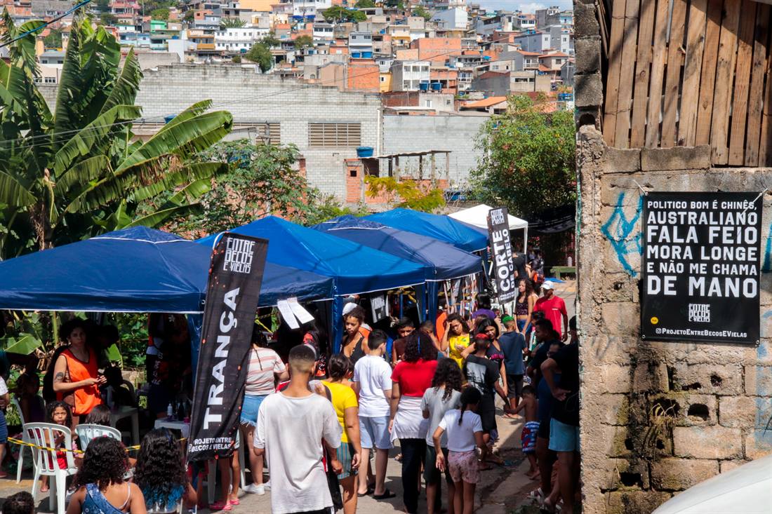 Feira comunitária movimentada nos becos da favela.