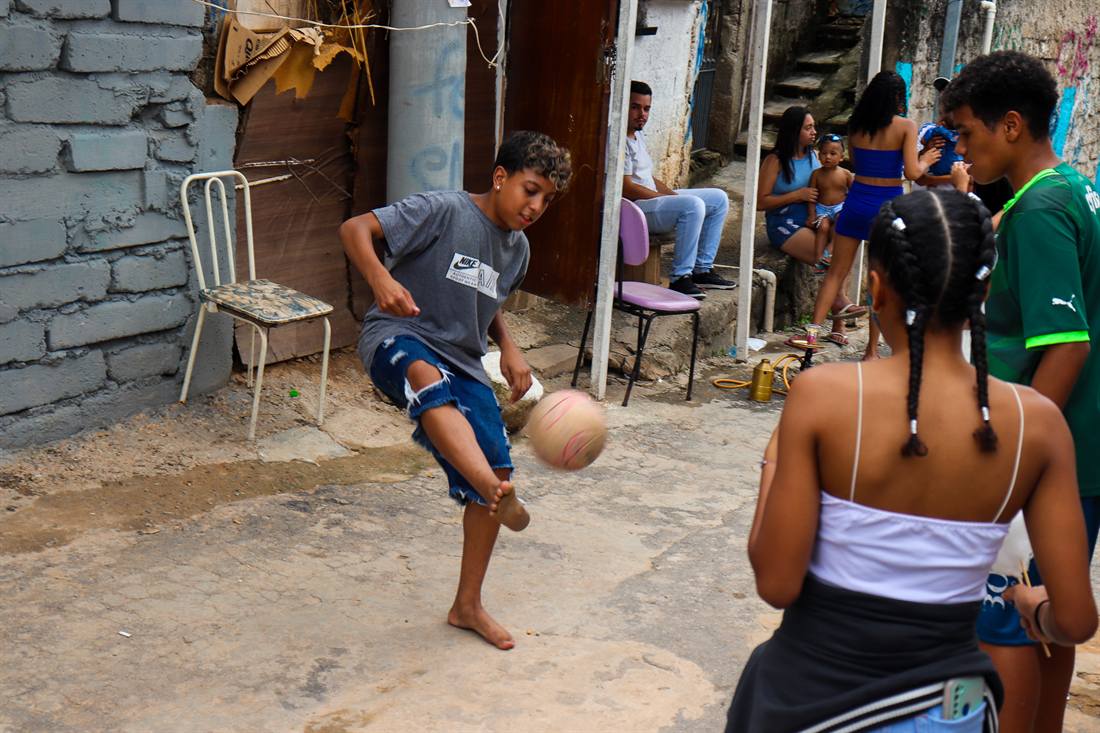 Menino domina uma bola de futebol em um beco da quebrada.